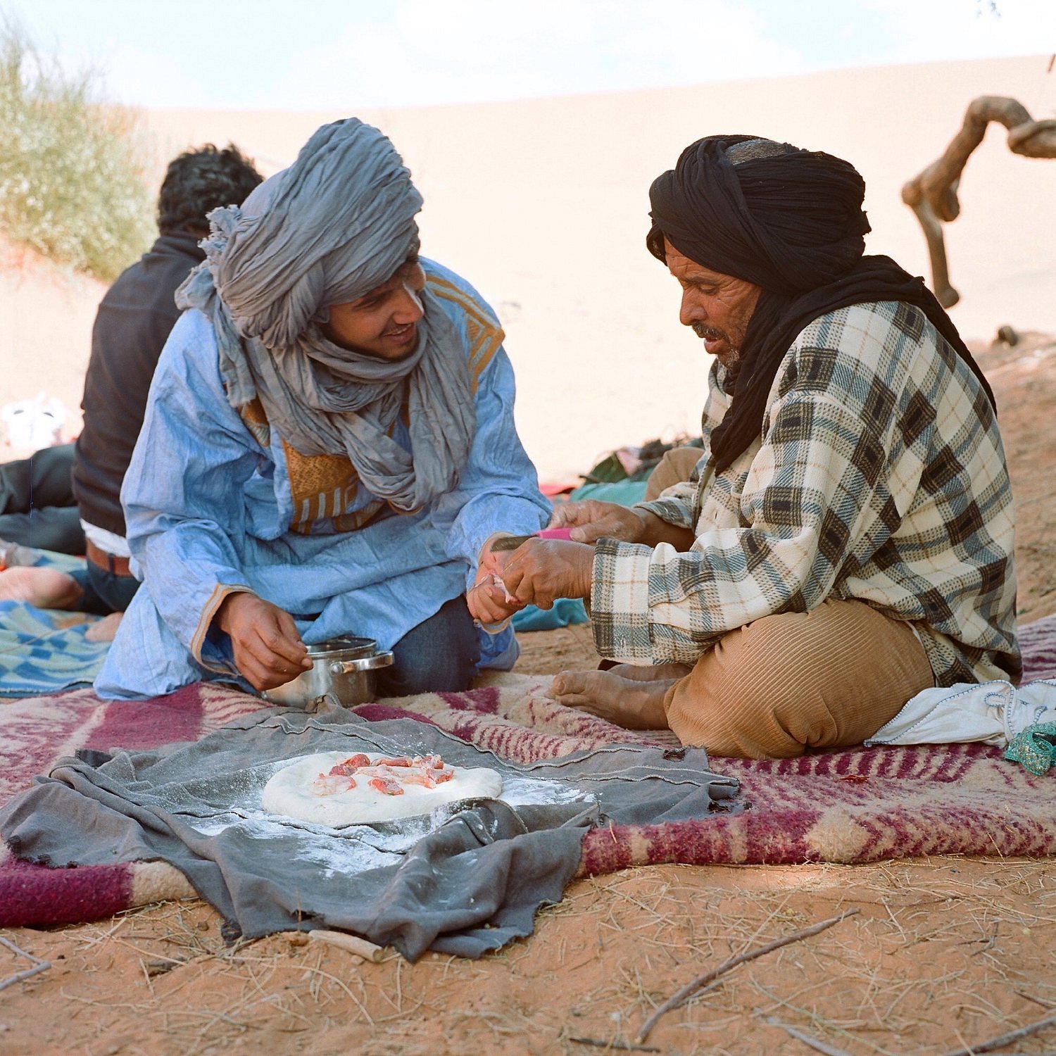 A Top Desert guide and camp cook preparing traditional Berber pizza in the Moroccan Sahara